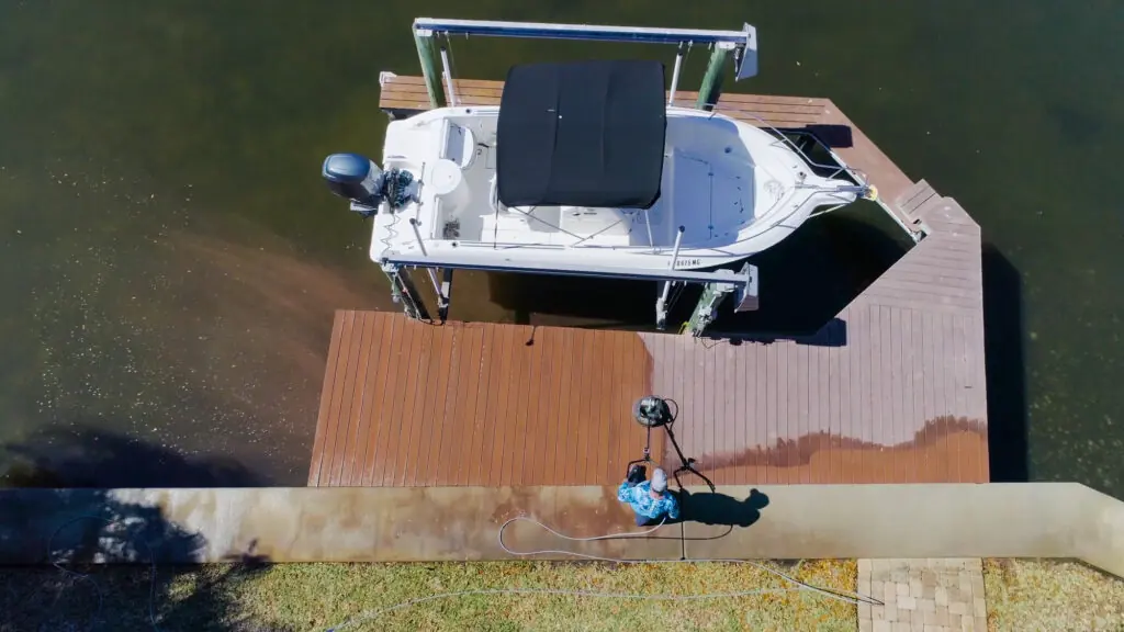 Overhead view of a Sunshine technician cleaning a dock next to a moored boat.