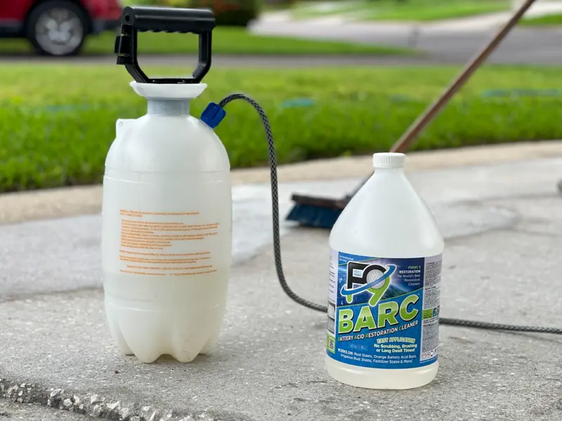 An F9 BARC rust remover bottle and pump sprayer set on a concrete driveway before treatment.